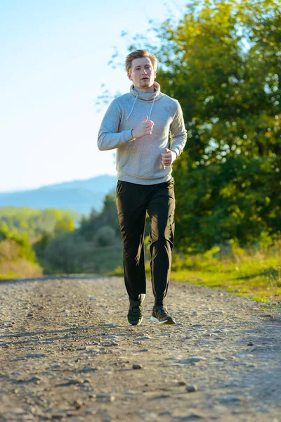 Man jogging in rural nature at beautiful summer day. Sport fitness model caucasian ethnicity training outdoor. — Stock Photo, Image