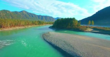 4k UHD hava görüntüsü. Güneşli yaz sabahında taze soğuk dağ nehri üzerinde alçak uçuş. Horisont 'ta yeşil ağaçlar ve güneş ışınları