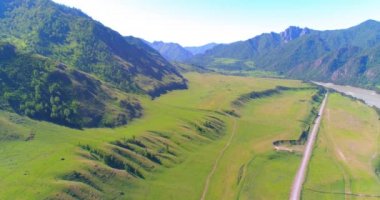 Güneşli yaz sabahında havadan kırsal dağ yolu ve çayır. Asfalt karayolu ve nehir.