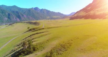 Güneşli yaz sabahında havadan kırsal dağ yolu ve çayır. Asfalt karayolu ve nehir.