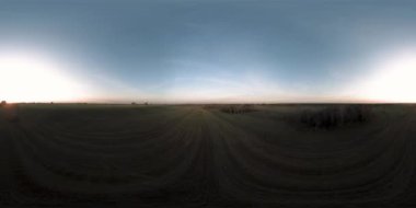 360 hava manzaralı. Güneşli bir sonbahar akşamında sonsuz yeşil tarlaları olan yaz manzarasının üzerinde alçak uçuş. Ufuktaki güneş ışınları. Hızlı yatay hareket. Sabitlendi ve yamandı.