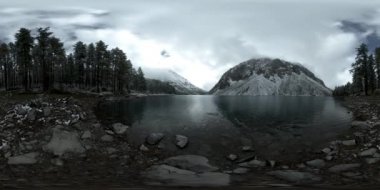 Dağ Gölü 'nün kış zamanı 360 Vr. Vahşi doğa ve dağ vadisi. Çam ağaçlarından yeşil orman ve gökyüzünde hızlı bulutlar.