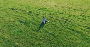 Yeşil çimlerin üzerinde sarı kırsal alanda not defteri olan bir adamın etrafında alçak yörünge uçuşları..