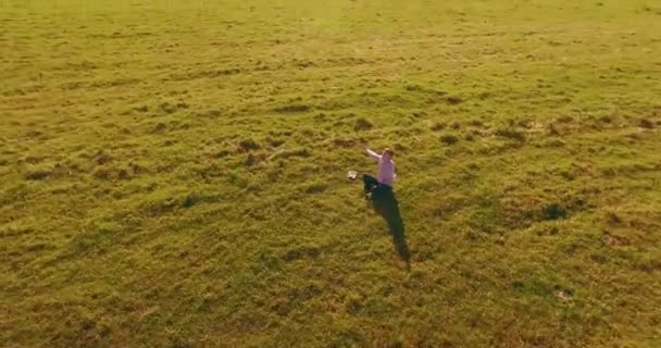 Basso volo orbitale intorno all'uomo su erba verde con blocco note al campo rurale giallo. — Video Stock