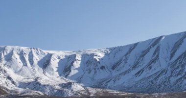 Güneşin kar dağının tepesinde kristal berrak gökyüzünde hareketinin zamanı. Sonbahar otlağında sarı çimenler. Vahşi sonsuz doğa..