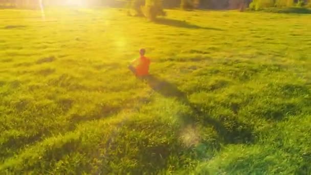 Lage hoogte radiale vlucht over sport yoga man op perfect groen gras. Zonsondergang in de bergen. — Stockvideo