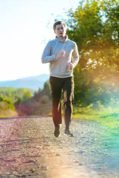 Чоловік біжить у сільській місцевості в прекрасний літній день. Спортивна фітнес-модель кавказької етнічної підготовки на відкритому повітрі . — стокове фото