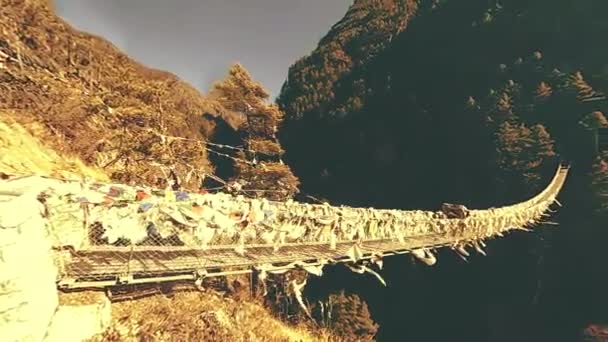 Largest suspension bridge in Khumbu valley with colorful Tibetan prayer flags. Wild Himalayas high altitude nature and mount valley. Rocky slopes covered with trees. Base camp of Everest peak trek. — Stock Video