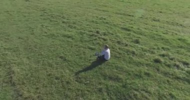Yeşil çimlerin üzerinde sarı kırsal alanda not defteri olan bir adamın etrafında alçak yörünge uçuşları..
