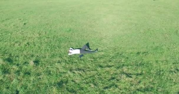 Vuelo orbital bajo alrededor del hombre sobre hierba verde con bloc de notas en el campo rural amarillo. — Vídeos de Stock