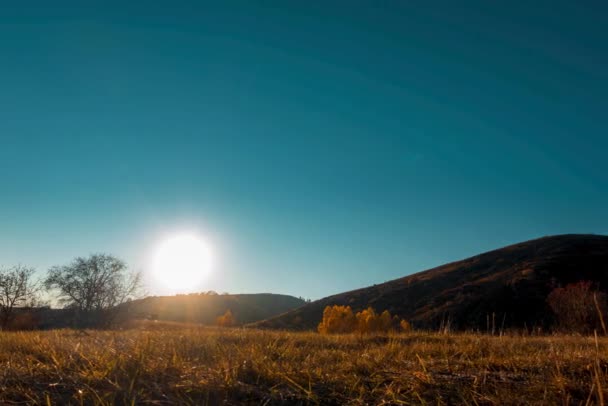 Tempo-lapse del prato di montagna all'ora del tramonto di autunno o di estate. Natura selvaggia e campo rurale. Cielo limpido, alberi, erba verde e gialla, raggi di sole all'orizzonte. Movimento cursore motorizzato. — Video Stock