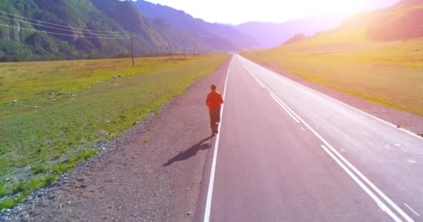 完璧なアスファルト道路でスポーティな男の前で低高度飛行 — ストック動画