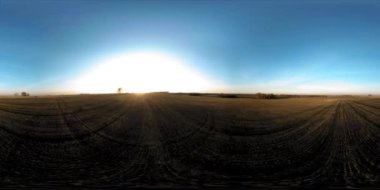 360 hava manzaralı. Güneşli bir sonbahar akşamında sonsuz yeşil tarlaları olan yaz manzarasının üzerinde alçak uçuş. Ufuktaki güneş ışınları. Hızlı yatay hareket. Sabitlendi ve yamandı.