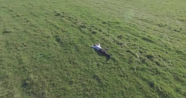 Низкоорбитальный полет вокруг человека на зеленой траве с блокнотом на желтом сельском поле. — стоковое видео