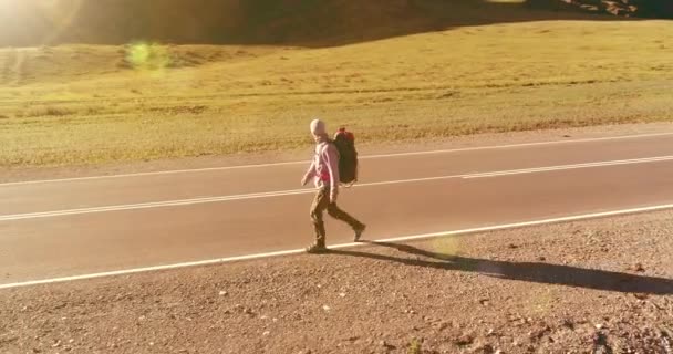 Vol au-dessus de l'auto-stoppeur touristique marchant sur la route asphaltée. Grande vallée rurale au jour d'été. Sac à dos randonneur gars. — Video