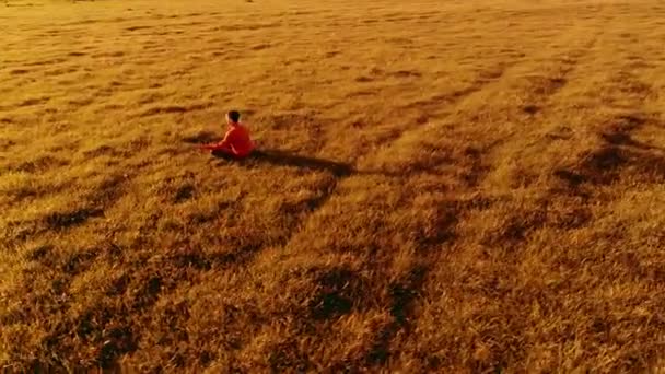 Vôo radial de baixa altitude sobre homem de ioga esporte na grama verde perfeita. Pôr do sol na montanha. — Vídeo de Stock