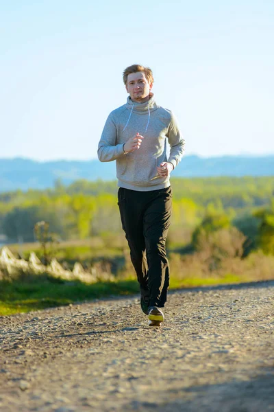 Hombre corriendo en la naturaleza rural en el hermoso día de verano. Deporte fitness modelo caucásico etnia entrenamiento al aire libre. —  Fotos de Stock