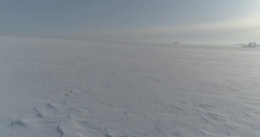 Soğuk kış kutup bölgesinin insansız hava görüntüsü, ufukta karla kaplı ağaçlar, buz nehri ve güneş ışınları. Aşırı düşük sıcaklık havası.