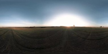 360 hava manzaralı. Güneşli bir sonbahar akşamında sonsuz yeşil tarlaları olan yaz manzarasının üzerinde alçak uçuş. Ufuktaki güneş ışınları. Hızlı yatay hareket. Tarım arazisi insansız hava aracı atışı. Dengeli