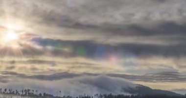 Akşam güneşlerinin zamanı dağlardaki soğuk, sisli bulutların arasından yükseliyor. Dağ sisinde gün batımı. Kamera hareketi.