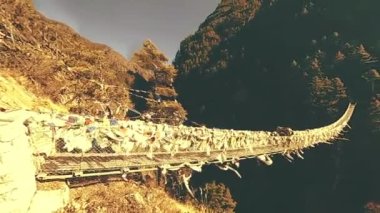 Khumbu vadisindeki en büyük asma köprü renkli Tibet dua bayraklarıyla. Vahşi Himalayalar yüksek irtifa doğa ve dağ vadisi. Ağaçlarla kaplı kayalık yamaçlar. Trek alanı ana kampa gidiyor.