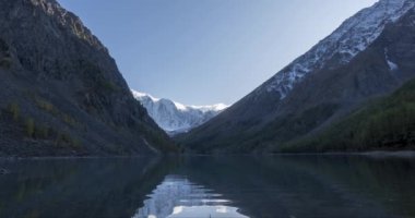 4K UHD dağ gölü zaman ayarlı yaz veya sonbahar saatlerinde. Vahşi doğa ve kırsal dağ vadisi. Çam ağaçlarından oluşan yeşil orman ve gökyüzünde hızlı bulutlar. Motorlu doli kaydırma hareketi