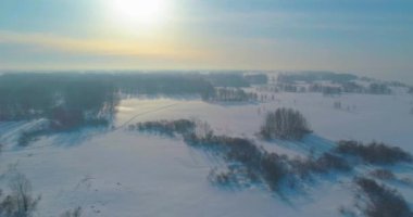 Soğuk kış kutup bölgesinin insansız hava görüntüsü, ufukta karla kaplı ağaçlar, buz nehri ve güneş ışınları. Aşırı düşük sıcaklık havası.
