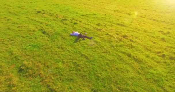 空中展望台 人間の周りの低軌道飛行は 黄色の田園地帯にノートパッドを持つ緑の芝生に横たわっていました 普段着だ 太陽光線 放射線運動 — ストック動画