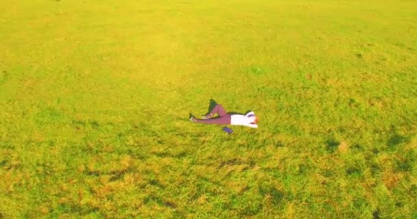 空中展望台 人間の周りの低軌道飛行は 黄色の田園地帯にノートパッドを持つ緑の芝生に横たわっていました 普段着だ 太陽光線 放射線運動 — ストック動画