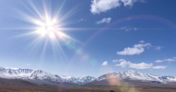 4K超高清太阳在晶莹的天空中移动的时间 雪山顶上布满了云彩 秋天的高原地区黄草丛生 野生无尽的天性 照相机运动 — 图库视频影像