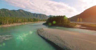 4k UHD hava görüntüsü. Bulutlu yaz sabahında taze soğuk dağ nehri üzerinde alçak uçuş. Horisont 'ta yeşil ağaçlar ve güneş ışınları. Hızlı yatay hareket