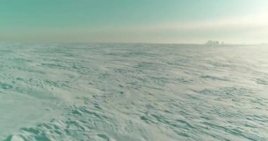 Soğuk kış kutup bölgesinin insansız hava görüntüsü, ufukta karla kaplı ağaçlar, buz nehri ve güneş ışınları. Aşırı düşük sıcaklık havası.