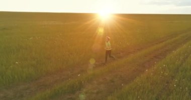 Sportif bir çocuğun havadan çekimleri buğday tarlasından geçiyor. Kırsal çayırlarda akşam sporu alıştırmaları. Mutlu bir çocukluk sağlıklı bir yaşam biçimidir. Açık havada koşma transferi. Radikal hareket, güneş