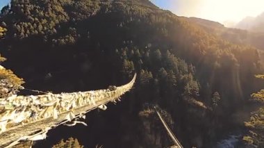 Khumbu vadisindeki en büyük asma köprü renkli Tibet dua bayraklarıyla. Vahşi Himalayalar yüksek irtifa doğa ve dağ vadisi. Ağaçlarla kaplı kayalık yamaçlar. Trek alanı ana kampa gidiyor.