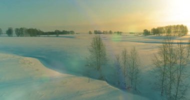 Soğuk kış kutup bölgesinin insansız hava görüntüsü, ufukta karla kaplı ağaçlar, buz nehri ve güneş ışınları. Aşırı düşük sıcaklık havası. Sibirya