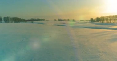 Soğuk kış kutup bölgesinin insansız hava görüntüsü, ufukta karla kaplı ağaçlar, buz nehri ve güneş ışınları. Aşırı düşük sıcaklık havası. Sibirya