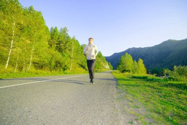 Koşan adam güzel bir yaz gününde şehir parkında koşuyor. Spor fitness modeli Kafkasya etnik köken eğitimi.