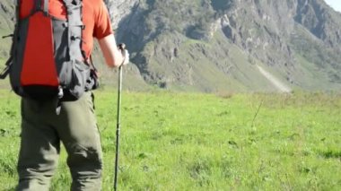 Sırt çantası ile yeşil dağ çayır üzerinde yürüyen adam Fhd Hiking. Güneşli havada seyahat turizm. Yaz spor ve eğlence kavramı.