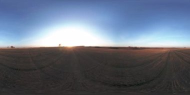 360 hava manzaralı. Güneşli bir sonbahar akşamında sonsuz yeşil tarlaları olan yaz manzarasının üzerinde alçak uçuş. Ufuktaki güneş ışınları. Hızlı yatay hareket. Tarım arazisi insansız hava aracı atışı. Dengeli