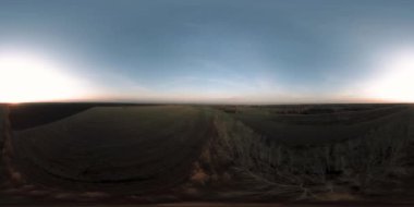 360 hava manzaralı. Güneşli bir sonbahar akşamında sonsuz yeşil tarlaları olan yaz manzarasının üzerinde alçak uçuş. Ufuktaki güneş ışınları. Hızlı yatay hareket. Tarım arazisi insansız hava aracı atışı. Dengeli