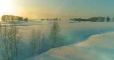 Soğuk kış kutup bölgesinin insansız hava görüntüsü, ufukta karla kaplı ağaçlar, buz nehri ve güneş ışınları. Aşırı düşük sıcaklık havası. Sibirya