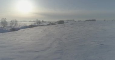 Soğuk kış kutup bölgesinin insansız hava görüntüsü, ufukta karla kaplı ağaçlar, buz nehri ve güneş ışınları. Aşırı düşük sıcaklık havası.