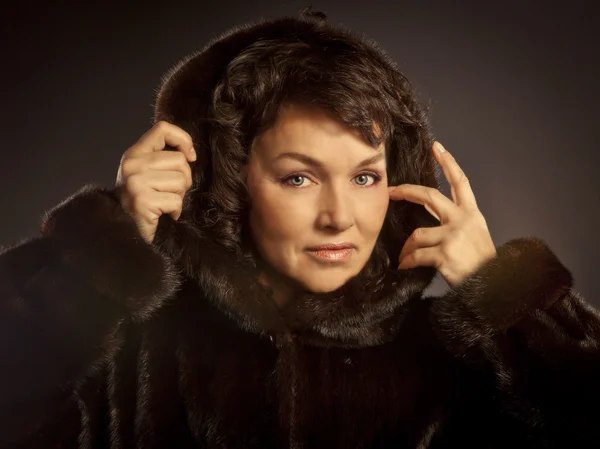 Young woman in a mink coat posing in studio — Stock Photo, Image