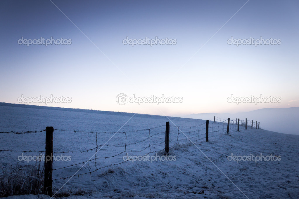 Sunset with barbed wires on frosty winter day