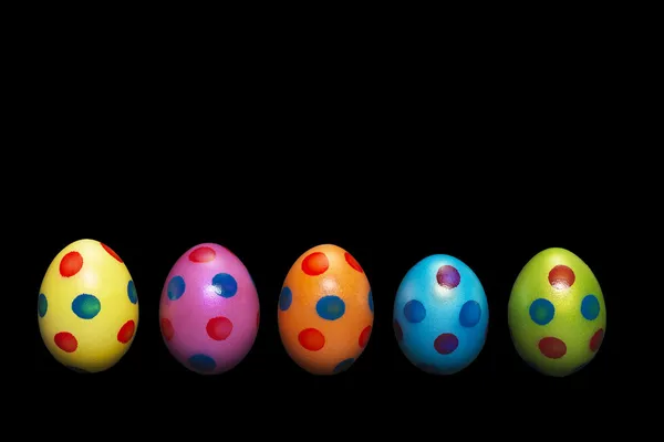 Linea di uova di Pasqua colorate su sfondo nero — Foto Stock