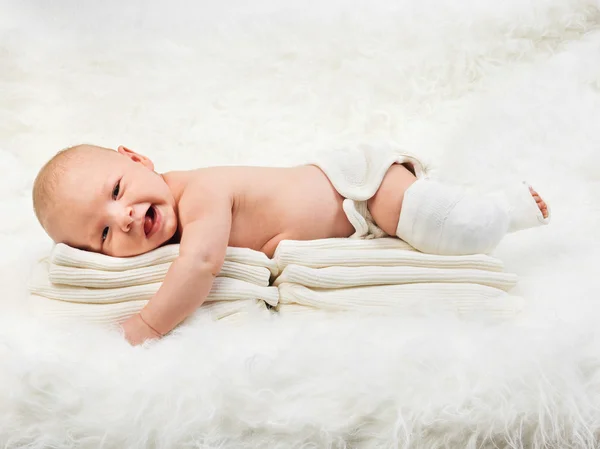 Niedlicher kleiner Junge entspannt sich auf einem Stapel Handtücher Stockbild