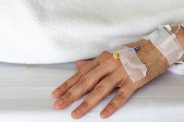 Woman's hand piercing needle to give saline solution