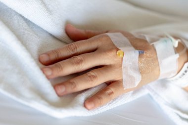 Woman's hand piercing needle to give saline solution