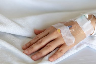 Woman's hand piercing needle to give saline solution