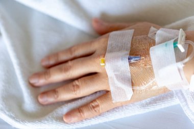 Woman's hand piercing needle to give saline solution